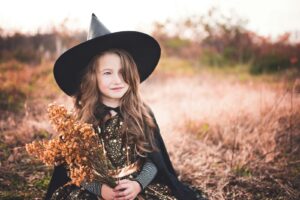 Girl in a witch costume in autumn leaves, Halloween with braces guide from BCR Orthodontics in Winston-Salem NC